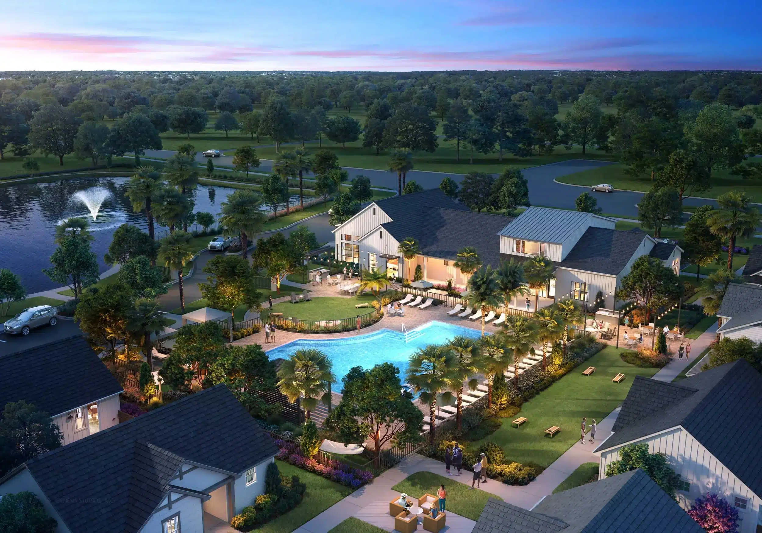 Aerial view of a residential community clubhouse with a large outdoor pool, lounge chairs, palm trees, gathering areas, and a pond with a water fountain at sunset.